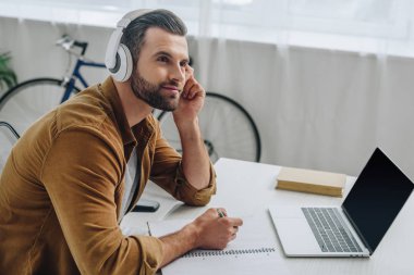 iyi görünümlü adam müzik dinleme, kalem tutan ve uzağa bakarak 