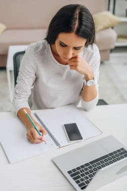 high angle view of beautiful woman writing in notebook with pencil  clipart