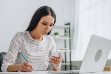 kalem ve akıllı telefon tutan ile defterde yazma güzel kadın 