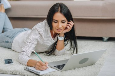 kulaklıklar ile güzel kadın yerde yatan ve not defterine yazma 