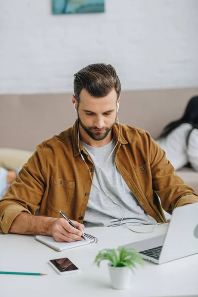 Schöner Mann Schreibt Notizbuch Mit Stift Und Hört Musik — Stockfoto