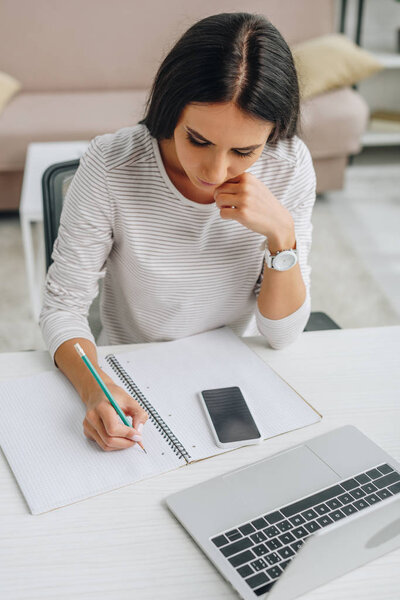 high angle view of beautiful woman writing in notebook with pencil 