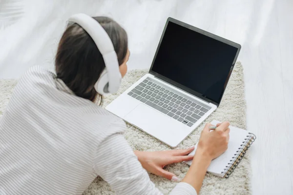 Achteraanzicht Van Vrouw Met Hoofdtelefoon Liggend Vloer Vasthouden Van Pen — Stockfoto