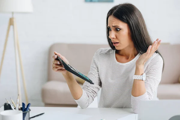 Mujer Atractiva Conmocionada Sosteniendo Calculadora Mirándola —  Fotos de Stock