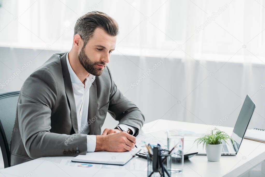 handsome man in formal wear writing in notebook with pen 