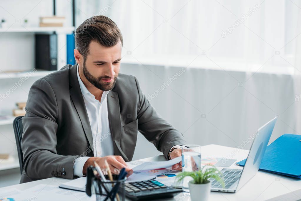 handsome man in formal wear reading document in apartment 