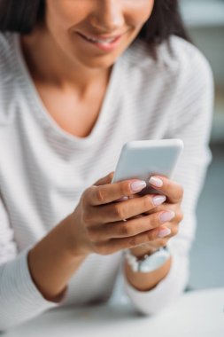 dairede akıllı telefon kullanarak genç yetişkin kadının kırpılmış görünümü 