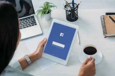 ekranda facebook web sitesi ile dijital tablet tutan kadın kırpılmış görünümü 