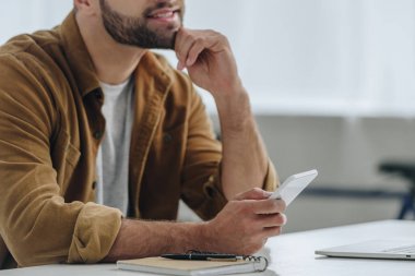 dairede akıllı telefon tutan gömlek adam kırpılmış görünümü 