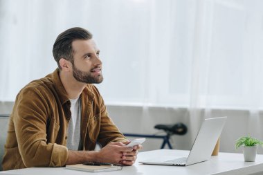 yakışıklı ve rüya gibi adam akıllı telefon tutan ve yukarı bakıyor 