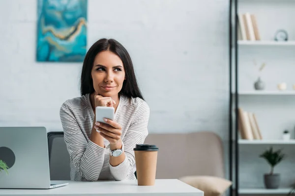 Attraktive Und Brünette Frau Hält Smartphone Der Hand Und Schaut — Stockfoto