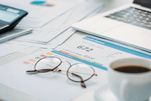 selective focus of credit report, glasses, cup with coffee and laptop