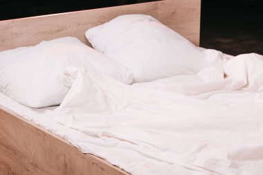 siyah yatak odasında beyaz temiz yatak çarşafları üzerinde yastık 