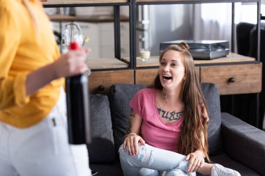 oturma odasında kız arkadaşı yakınında ayakta iken şarap ve şarap gözlükleri lezbiyen tutan şişe kısmi görünümü