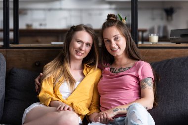 oturma odasında kanepede otururken kucaklayan iki güzel Lezbiyenler