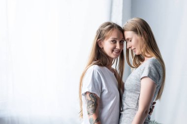 yatak odasında kucaklayan t-shirt iki gülümseyen lezbiyenler