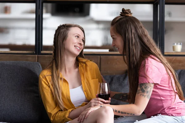 Smiling Lesbian Holding Wine Glass Looking Girlfriend While Sitting Sofa — Stock Photo, Image