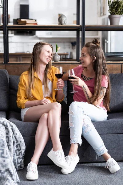 Dos Lesbianas Sosteniendo Copas Vino Mirándose Mientras Sentaban Sofá Sala — Foto de Stock