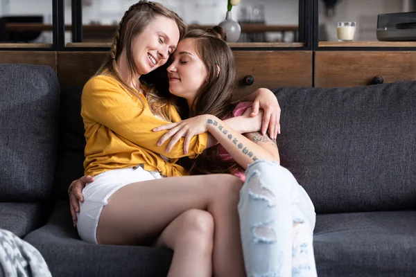 Duas Lésbicas Bonitas Abraçando Enquanto Sentado Sofá Sala Estar — Fotografia de Stock