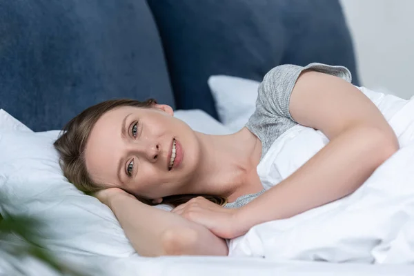 Bonita Sorrindo Jovem Mulher Deitada Cama Olhando Para Câmera — Fotografia de Stock