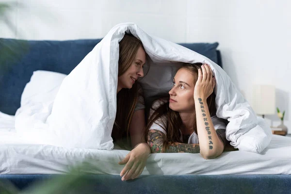 Dos Lesbianas Tumbadas Debajo Una Manta Mirándose Dormitorio — Foto de Stock