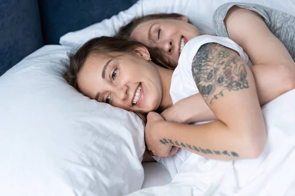 Twee Glimlachende Lesbiennes Omarmen Terwijl Liggend Bed — Stockfoto