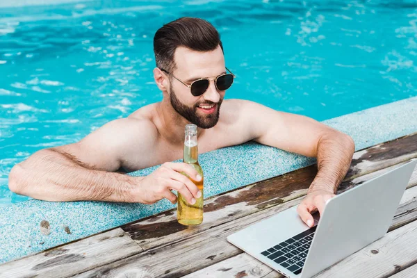 Hombre Barbudo Alegre Gafas Sol Usando Ordenador Portátil Mientras Sostiene —  Fotos de Stock