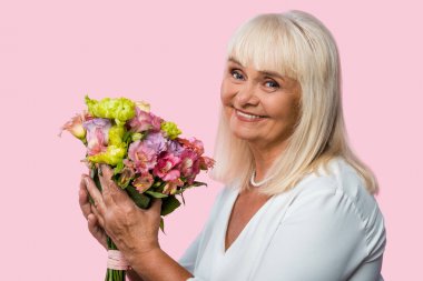 pembe izole çiçek açan çiçekler tutan mutlu yaşlı kadın 