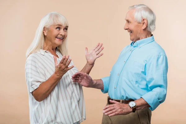 Glückliche Seniorin Gestikuliert Während Sie Ehemann Isoliert Auf Beige Betrachtet — Stockfoto