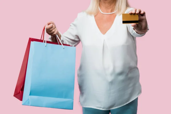 Beskuren Syn Pensionerad Kvinna Hålla Shoppingväskor Och Kreditkort Isolerade Pink — Stockfoto