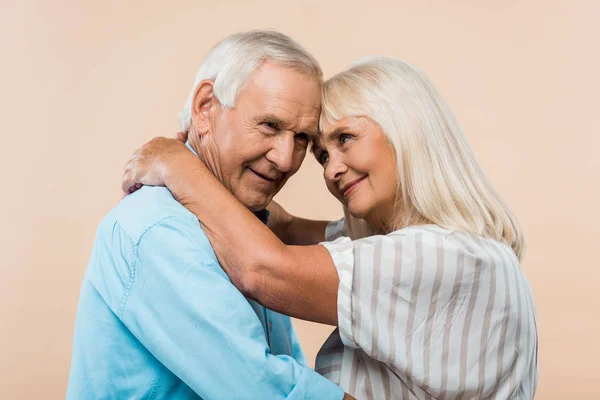 Ευτυχισμένη Συνταξιούχος Γυναίκα Κοιτάζοντας Τον Άντρα Αγκάλιασμα Απομονωμένος Στο Μπεζ — Φωτογραφία Αρχείου