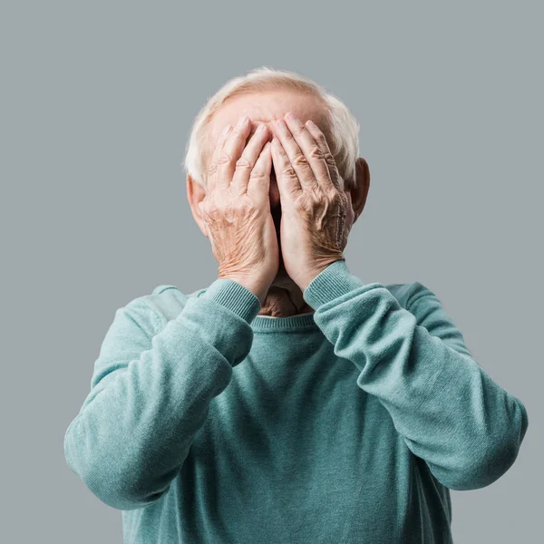 senior man with grey hair covering face with hands isolated on grey