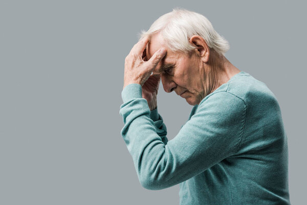 exhausted and sad retired man touching head isolated on grey 