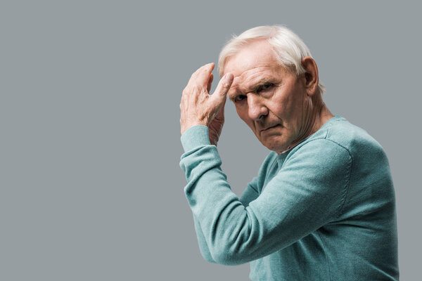 exhausted and upset retired man gesturing and looking at camera isolated on grey 