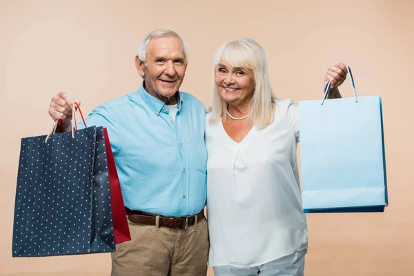 Glada Pensionerade Par Hålla Shoppingväskor Och Leende Isolerade Beige — Stockfoto