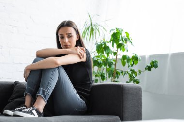evde kanepede otururken depresyon ve ağlama muzdarip üzgün genç kadın