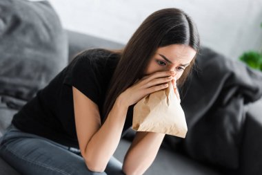 evde panik atak geçiren genç kadın kağıt torbaya nefes alıyor