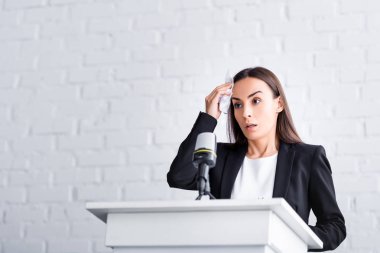 endişeli öğretim görevlisi, glossophobia muzdarip, podyum tribün üzerinde dururken alnına yakın peçete tutan