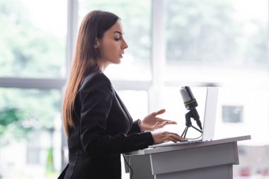 podyum tribününden konuşurken çekici, kendine güvenen öğretim görevlisi gesturing