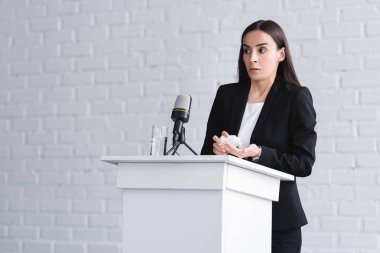 pretty lecturer, suffering from glossophobia, standing on podium tribune and holding container with pills clipart