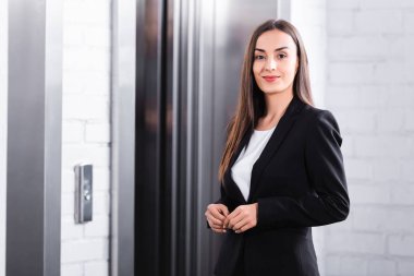 asansör beklerken kameraya gülümseyen güzel iş kadını