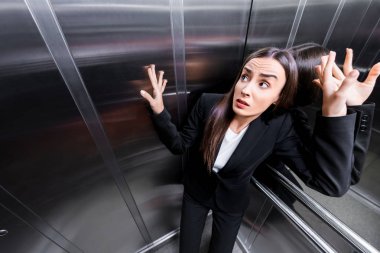 young scared businesswoman suffering from claustrophobia in elevator clipart