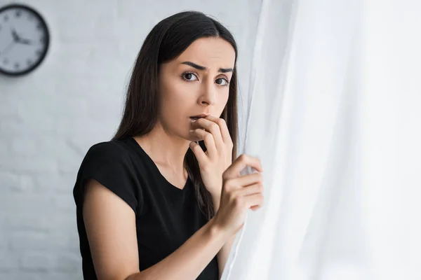 Mujer Joven Asustada Mirando Cámara Mientras Está Pie Junto Ventana —  Fotos de Stock