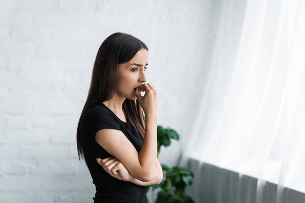 upset young woman looking away while suffering from depression at home