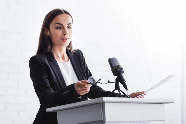 Vacker Positiv Föreläsare Hålla Glasögon Medan Står Podium Tribune — Stockfoto