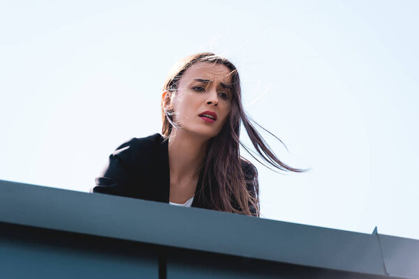 young businesswoman, suffering from fear of heights, looking down rooftop
