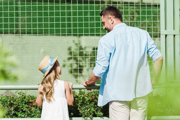 selective focus of cheerful father and daughter looking at each other in zoo 