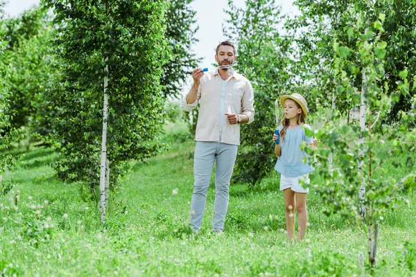 Fokus Selektif Ayah Dan Anak Meniup Gelembung Sabun Dekat Pohon — Stok Foto