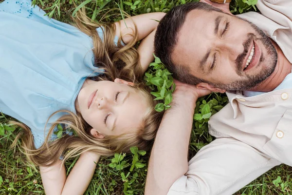 stock image top view of happy father and daughter lying on green grass 