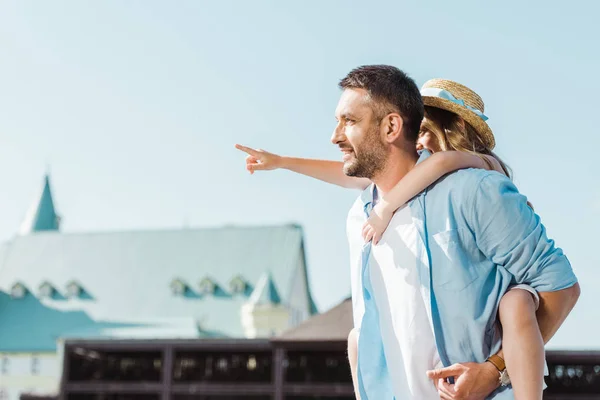 Homem Alegre Piggybacking Filha Apontando Com Dedo Perto Edifício — Fotografia de Stock